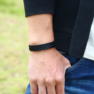 Bracciale da uomo minimalista in pelle nera con trama intrecciata su sfondo esterno