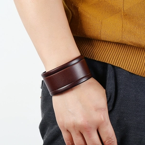 Close-up of a men's vintage dark brown wide leather wristband worn on a wrist