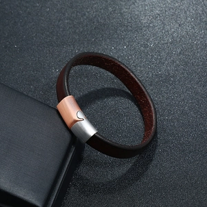Detail of a brown leather bracelet with a heart-shaped magnetic clasp on a display box
