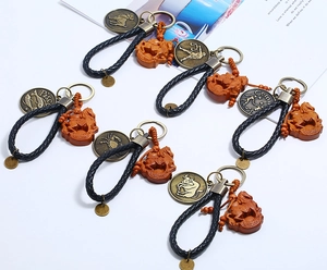 Close-up of woven leather zodiac keychains with vintage metal plates and wooden horse pendants