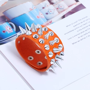 Orange leather punk bracelet detail with three rows of silver metal cone spikes and snaps