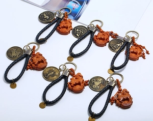 Detail of woven leather keychains with bronze zodiac signs and wooden horse pendants