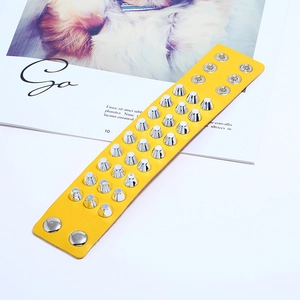 Detail view of yellow leather punk bracelet featuring silver metal conical studs and snaps