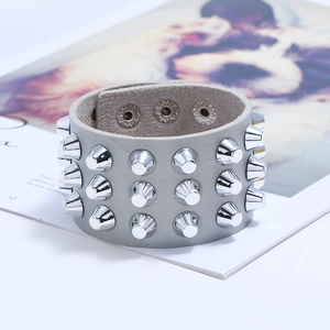 Close-up of triple-row silver cone studs on a wide punk leather bracelet with snap buttons