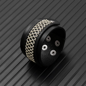 Close-up of black leather wide bracelet with white cross-stitching and metal snap buttons