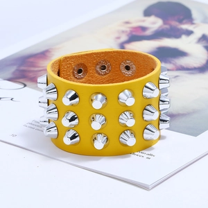 Macro shot of punk style yellow leather bracelet featuring three rows of silver metal spikes