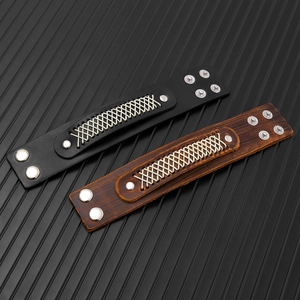Detail of wide multi-layer leather bracelets in black and brown with woven rope and snap buttons