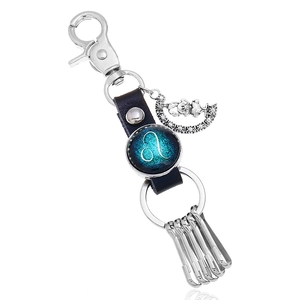 Detail of a Leo constellation leather keychain with a moon bear charm and silver hooks