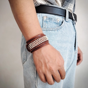 Close-up of wide brown leather bracelet with woven details on a male wrist