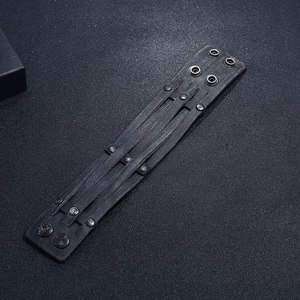 Détail d'un bracelet punk vintage en cuir noir avec rivets métalliques et pressions