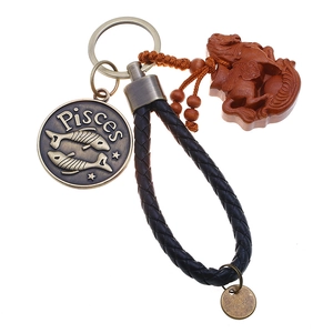 Detail of Pisces keychain with black braided leather strap and engraved metal pendant