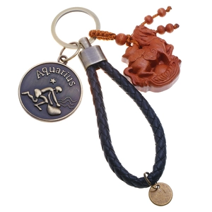 Macro shot of Aquarius zodiac medal and carved wooden horse pendant on leather keychain