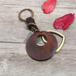 Vintage leather and round wood keychain with bronze metal ring on a wooden background