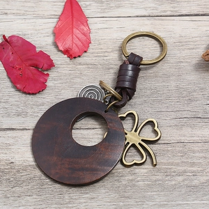 Vintage woven leather keychain with dark brown wooden pendant and bronze clover charm