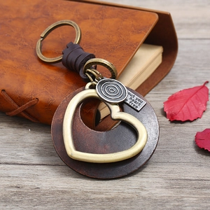 Vintage leather keychain with wooden heart charm and bronze metal accents on leather desk
