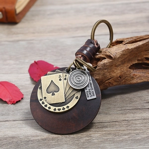 Vintage braided leather keychain with wooden base and antique bronze charms on desk