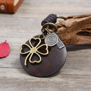 Vintage leather woven keychain with four-leaf clover heart charm and wooden base