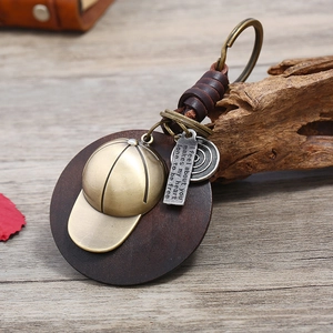Retro woven leather keychain featuring bronze baseball cap pendant and wooden base