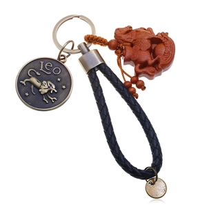 Close-up of leather braided Leo keychain with bronze zodiac pendant and wooden horse charm