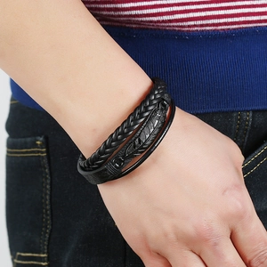 Close-up of a men's black multi-layer leather bracelet with a vintage feather charm detail