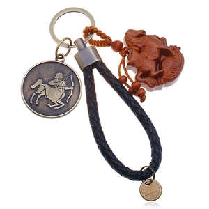 Macro detail of leather woven keychain with Sagittarius bronze disc and wooden horse pendant