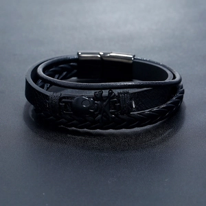 Detail of black multi-layer braided leather bracelet with black skull and magnetic clasp