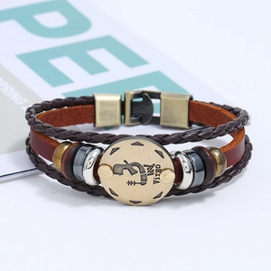 Detail of a vintage braided leather bracelet featuring a brass Virgo zodiac sign charm