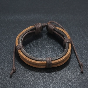 Vintage layered brown woven leather bracelet with adjustable cord on black background