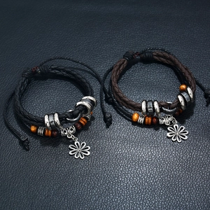 Detail of woven leather bracelets with daisy charms, wooden beads, and adjustable cords