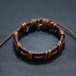 Vintage dark brown braided leather bracelet with adjustable cord on black background