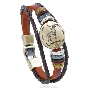 Detailed macro view of Capricorn charm on a vintage woven multilayer leather bracelet