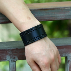 Punk style black wide leather bracelet with four rows of perforated holes on a male wrist