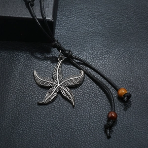 Ethnic alloy starfish pendant necklace with black wax cord on leather background