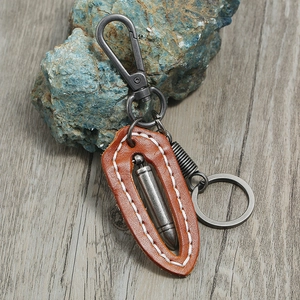 Retro brown leather keychain with bullet pendant and matte black carabiner on stone background