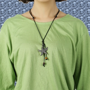 Vintage starfish pendant long necklace with ethnic wax cord worn on a green sweater