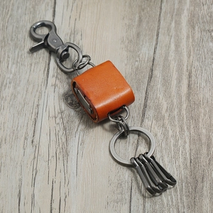 Macro view of retro orange leather keychain with four dark grey metal lobster claw hooks