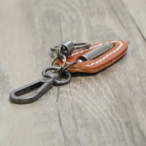Retro brown leather keychain with metal bullet pendant on light wood background
