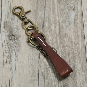 Retro brown genuine leather keychain with vintage bronze alloy lobster clasp on wood