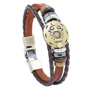 Detail of hand-woven leather bracelet featuring Cancer zodiac sign engraved on metal charm