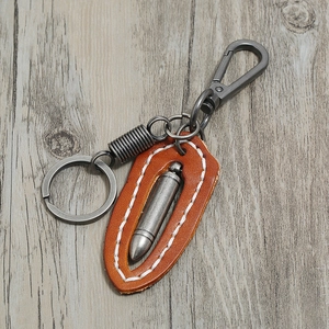 Retro brown leather keychain with bullet pendant and metal snap hook on wood background