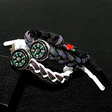 Close-up of woven couple bracelets featuring a built-in compass and red heart detail