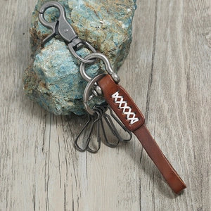 Retro brown leather keychain with silver alloy carabiner and spring hooks on stone background