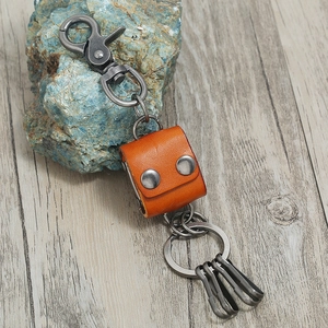 Vintage cowhide leather keychain with metal lobster clasp and hooks on a wooden table