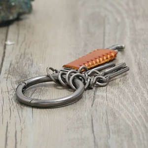 Vintage leather and alloy keychain with multiple rings and hooks on a rustic wood surface