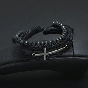 Multi-layer black braided leather bracelet with vintage silver cross and beads on a display