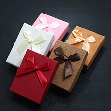 Set of five colorful textured jewelry boxes with matching silk ribbon bows on dark background