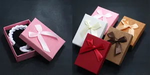 Various colored ribbon gift boxes with satin bows for woven bracelets shown on dark leather