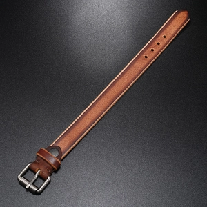 Close-up of vintage brown leather bracelet with aged metal buckle and refined texture