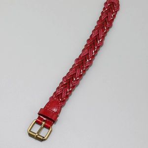 Detail view of red woven PU leather bracelet with vintage bronze buckle and rich texture