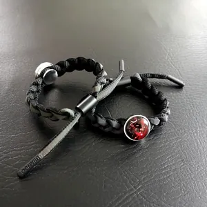 Dettaglio di bracciali intrecciati con ciondolo nebulosa rossa e punte in metallo incise